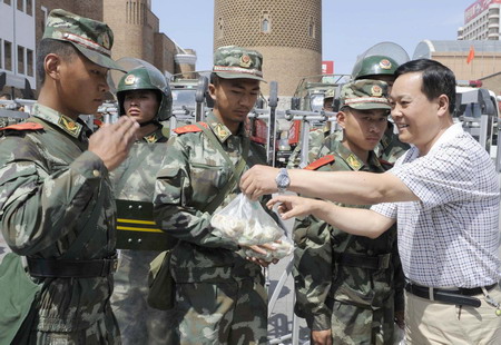 An employee of a construction company gives self-prepared dumplings to the public security forces whose intrepid presence spared the riot-plagued city from further unrests, in Urumqi, northwest China's Xinjiang Uygur Autonomous Region, Friday July 10, 2009. [Xinhua]