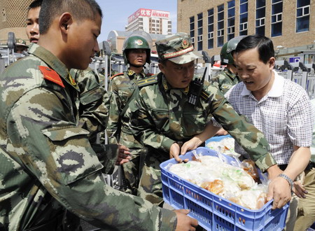 An employee of a construction company gives self-prepared dumplings to the public security forces whose intrepid presence spared the riot-plagued city from further unrests, in Urumqi, northwest China's Xinjiang Uygur Autonomous Region, Friday July 10, 2009. [Xinhua]