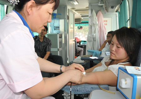 A citizen donates blood for the wounded of the July 5 riot in Urumqi on a blood collecting vehicle in Aksu, northwest China's Xinjiang Uygur Autonomous Region, July 10, 2009. [He Jun/Xinhua] 
