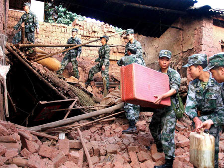 Rescuers help move belongings of local residents on the debris of a collapsed house in the earthquake-hit Yao'an County, southwest China's Yunnan Province, July 10, 2009. A 6.0-magnitude quake hit southwest China Thursday evening, killing one and injuring 342. [Xinhua]