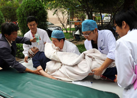 Doctors carry an injured man onto the stretcher at the People's Hospital of the earthquake-hit Yao'an County, southwest China's Yunnan Province, July 10, 2009. [Xinhua]