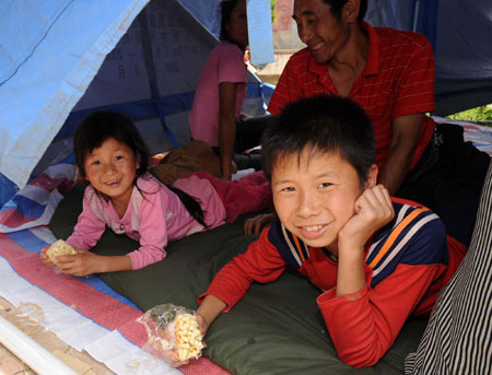 Children look out from a temporary tent in Yao'an County, southwest China's Yunnan Province, July 10, 2009. [Xinhua]