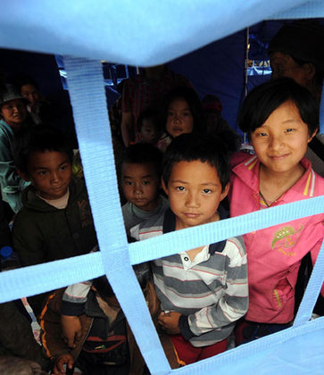  Children look out from a temporary tent in Yao'an County, southwest China's Yunnan Province, July 10, 2009. [Xinhua]