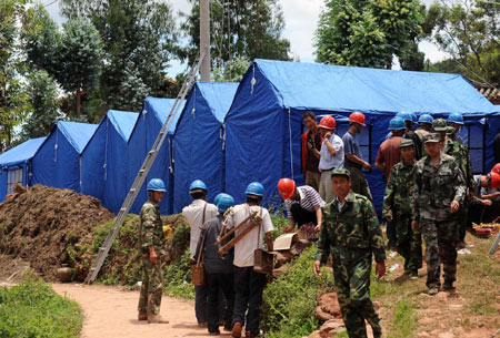 Resucers help set up temporary tents for local residents in the earthquake-hit Yao'an County, southwest China's Yunnan Province, July 10, 2009. [Xinhua] 