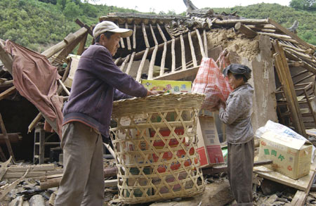 Villagers sort out daily necessities on the debris of a collapsed house in Yao'an County, southwest China's Yunnan Province, July 10, 2009. [Xinhua] 