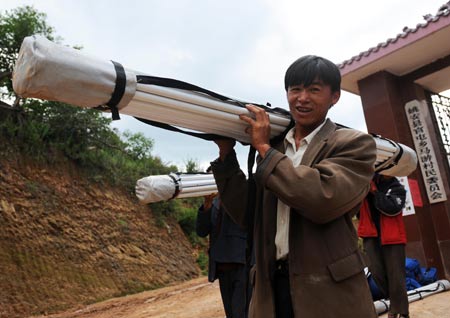 A villager of Yi ethnic group receives a relief tent at Mayou Village in Guantun Township of Yao'an County, southwest China's Yunnan Province, July 12, 2009. Now more than 20,000 earthquake victims have been placed in tents and have received basic relief materials. (Xinhua/Lin Yiguang) 