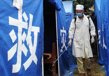 A health official wearing sanitation suits disinfects relief tents at Guantun Village in Guantun Township of Yao'an County, southwest China's Yunnan Province, July 12, 2009. Now more than 20,000 earthquake victims have been placed in tents and have received basic relief materials. (Xinhua/Lin Yiguang)