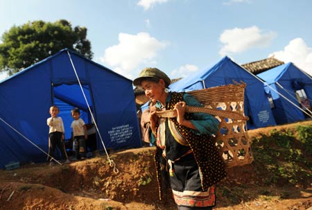 A villager of Yi ethnic group walks past tents at Mayou Village in Guantun Township of Yao'an County, southwest China's Yunnan Province, July 12, 2009. Now more than 20,000 earthquake victims have been placed in tents and have received basic relief materials. (Xinhua/Lin Yiguang)