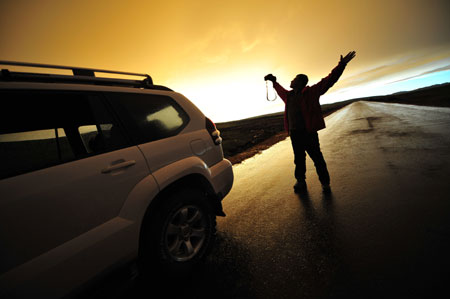 A tourist admires the sunset on the grassland of Qiangtang, southwest China's Tibet Autonomous Region, July 11, 2009.[Yang Guang/Xinhua] 