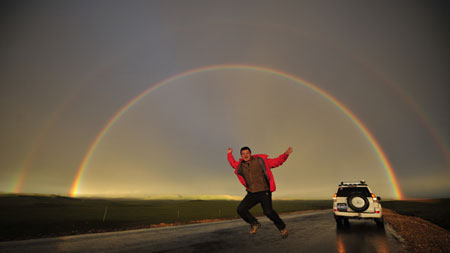 A tourist admires the sunset on the grassland of Qiangtang, southwest China's Tibet Autonomous Region, July 11, 2009.[Yang Guang/Xinhua]