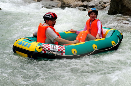 Two tourists enjoy the river-drifting tour on the air cushion vessel along the limpid brooks inside the Jiuwanxi Scenery Resort in Zigui County, central China's Hubei Province, July 11, 2009. The popularity of local recreational river-drifting tour has been on hikes for people to enjoy the coolness and lush scenery of the mountains and rivers in the canicular days.[Zheng Jiayu/Xinhua]