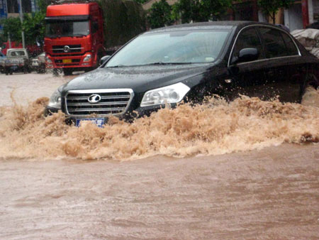 A car wades through the inundated street of the Daxian County in Dazhou City, southwest China's Sichuan Province, July 11, 2009. Strong rainfalls hit large area of Dazhou after the noon on Sunday. A total of 10,2000 residents were transfered to safe place and 2 persons were reported missing during the disaster. [Deng Liangkui/Xinhua]