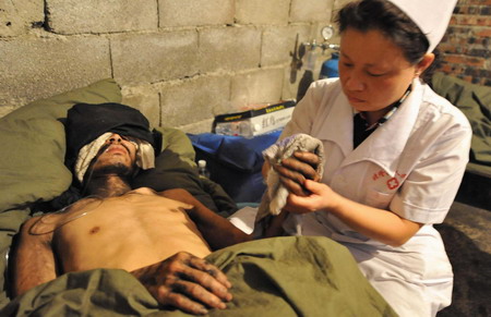 A medical worker attends to one of the three survivors who have been trapped in a flooded mine for 25 days at a makeshift tent in Qinglong county, southwest China's Guizhou Province Sunday, July 12, 2009. [Xinhua]