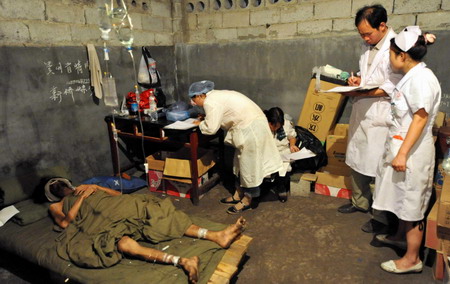 Medical workers attend to one of the three survivors who have been trapped in a flooded mine for 25 days at a makeshift tent in Qinglong county, southwest China's Guizhou Province Sunday, July 12, 2009. [Xinhua]