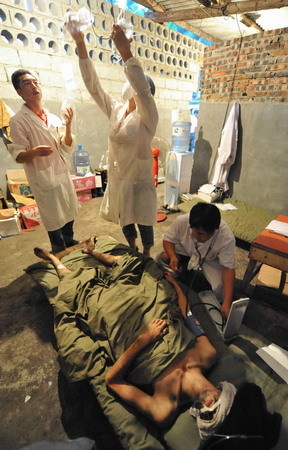  Medical workers attend to one of the three survivors who have been trapped in a flooded mine for 25 days at a makeshift tent in Qinglong county, southwest China's Guizhou Province Sunday, July 12, 2009. [Xinhua]