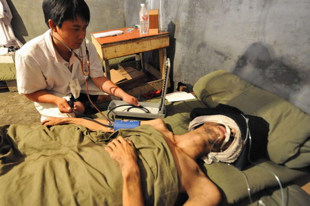 A medical worker attends to one of the three survivors who have been trapped in a flooded mine for 25 days at a makeshift tent in Qinglong county, southwest China's Guizhou Province Sunday, July 12, 2009. [Xinhua]