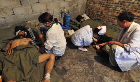 Medical workers attend to two of the three survivors who have been trapped in a flooded mine for 25 days at a makeshift tent in Qinglong county, southwest China's Guizhou Province Sunday, July 12, 2009. [Xinhua]