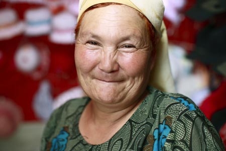A vendor smiles at a bazaar in Yining, northwest China's Xinjiang Uygur Autonomous Region, July 12, 2009. Local residents of various ethnic groups went to bazaars, their traditional markets, for shopping on Sunday. [Xinhua]