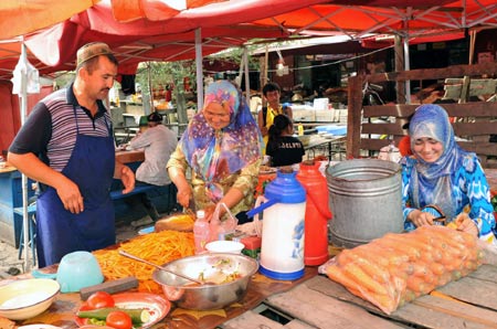 Vendors make food at a bazaar in Yining, northwest China's Xinjiang Uygur Autonomous Region, July 12, 2009. Local residents of various ethnic groups went to bazaars, their traditional markets, for shopping on Sunday. [Xinhua]