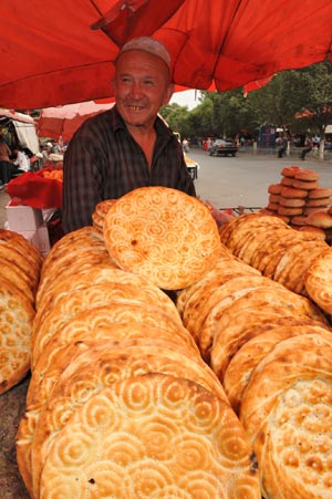 A vendor sells naan at a bazaar in Yining, northwest China's Xinjiang Uygur Autonomous Region, July 12, 2009. Local residents of various ethnic groups went to bazaars, their traditional markets, for shopping on Sunday. [Xinhua]