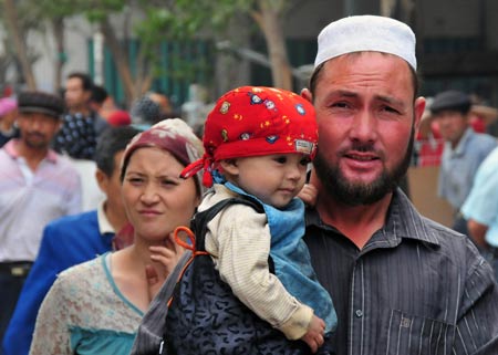 A man with a child in arm enjoys shopping at the largest bazaar in Aksu, northwest China's Xinjiang Uygur Autonomous Region, July 12, 2009. Local residents of various ethnic groups went to bazaars, their traditional markets, for shopping on Sunday. [Xinhua]