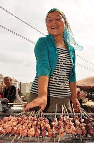 A woman sells kebab at the largest bazaar in Aksu, northwest China's Xinjiang Uygur Autonomous Region, July 12, 2009. Local residents of various ethnic groups went to bazaars, their traditional markets, for shopping on Sunday. [Xinhua]