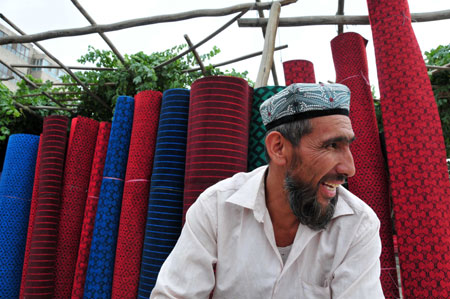 A vendor sells carpets at the largest bazaar in Aksu, northwest China&apos;s Xinjiang Uygur Autonomous Region, July 12, 2009. Local residents of various ethnic groups went to bazaars, their traditional markets, for shopping on Sunday. (Xinhua/Hou Jun) 