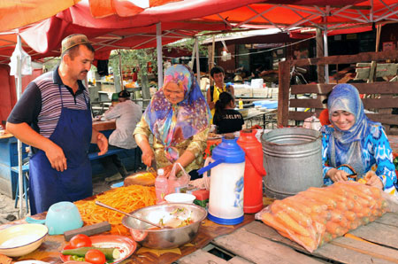 Vendors make food at a bazaar in Yining, northwest China&apos;s Xinjiang Uygur Autonomous Region, July 12, 2009. Local residents of various ethnic groups went to bazaars, their traditional markets, for shopping on Sunday. (Xinhua/He Junchang)