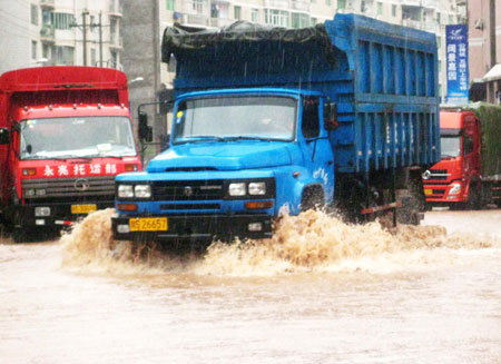 Vehicles wade through the inundated street at the Nanba Town of Yihan County in Dazhou City, southwest China's Sichuan Province, July 11, 2009. [Deng Liangkui/Xinhua]