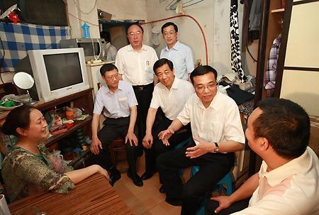 Chinese Vice Premier Li Keqiang (2nd R) talks with family members of Hu Jianhua who live in a dilapidated house in Yuzhong District of southwest China's Chongqing Municipality, July 10, 2009. Li made an inspection tour in Chongqing on July 10-11.(