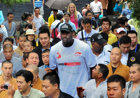 NBA Cleveland Cavaliers center Shaquille O'Neal (C) pose for a photo with monks and tourists during his promotional tour in Shaolin Temple, central China's Henan province, July 13, 2009. [Xinhua] 