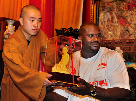 NBA Cleveland Cavaliers center Shaquille O'Neal (R) receives a Buddha statue, a gift from Shi Yongxin (not pictured), abbot of Shaolin Temple, during his promotional tour in Shaolin Temple, central China's Henan province, July 13, 2009. [Xinhua]