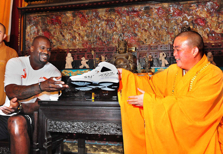 NBA Cleveland Cavaliers center Shaquille O'Neal (L) presents a basketball shoe with his signature to Shi Yongxin, abbot of Shaolin Temple, during his promotional tour in Shaolin Temple, central China's Henan province, July 13, 2009. [Xinhua]