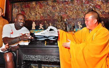 NBA Cleveland Cavaliers center Shaquille O'Neal (L) presents a basketball shoe with his signature to Shi Yongxin, abbot of Shaolin Temple, during his promotional tour in Shaolin Temple, central China's Henan province, July 13, 2009. [Xinhua]
