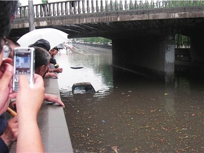 Two cars are submerged because of the heavy rain in Beijing on Monday, July 13, 2009. [The Beijing Times]