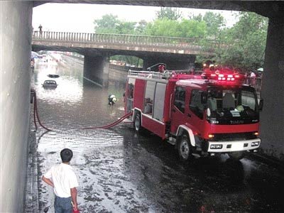 A fire engine pumps water out of a flooded road in Beijing on Monday, July 13, 2009. [The Beijing Times]