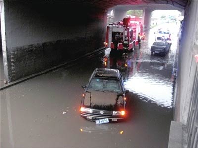 Vehicles are stranded in a flood caused by heavy rain in Beijing on Monday, July 13, 2009. [The Beijing Times]