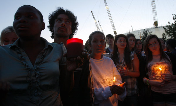 Fans of Michael Jackson hold their lighted candles as hundreds gathered at the O2 arena in London, seen behind, for a tribute celebration, Monday, July 13, 2009. Monday was to have been the opening night of Michael Jackson concerts at the arena but he died on June 25.