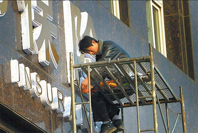 A worker fixes a signboard for an insurance company in Nanjing, capital of Jiangsu province. HIV/AIDS patients will be able to benefit from life insurance programs under a proposed rule. [File photo/China Daily] 