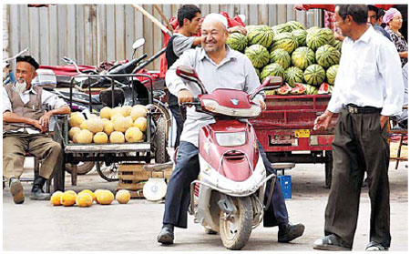 A Uygur farmer brings a truck-load of watermelons to sell at a bazaar in Kuche county, Xinjiang, last Friday. Xinhua 