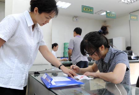 Student of Xinjiang University Tang Juan (R) fills in a form with the help of an employee at the Santunbei Branch of the Urumqi Post Bureau in Urumqi, capital of northwest China's Xinjiang Uygur Autonomous Region, on July 14, 2009. By now, all the 33 delivering outlets, 69 community outlets and 107 business outlets of the Urumqi Post Bureau have returned to normal work after the deadly riot on July 5. (Xinhua/Xu Liang) 