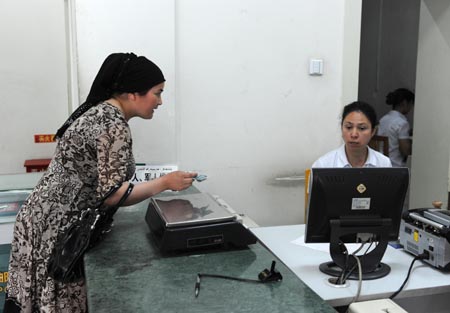A client conducts procedures at the Santunbei Branch of the Urumqi Post Bureau in Urumqi, capital of northwest China's Xinjiang Uygur Autonomous Region, on July 14, 2009. By now, all the 33 delivering outlets, 69 community outlets and 107 business outlets of the Urumqi Post Bureau have returned to normal work after the deadly riot on July 5. (Xinhua/Xu Liang)