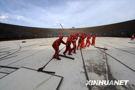 Workers drag the board of the float cabin inside the 100,000-cubic-meter crude oil storage tank located in the east part of Xinjiang Uygur Autonomous Region on Monday, July 13, 2009. Construction of China's biggest crude oil reserve base is going smoothly. [Photo: Xinhuanet] 