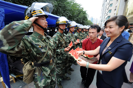 A policeman salutes when an employee of Rongdu Hotel sends watermelons to him in Urumqi, capital of northwest China's Xinjiang Uygur Autonomous Region, July 13, 2009. All walks of life in Urumqi have kept sending fruits, food and water to policemen who are ensuring the security here in recent days. [Xinhua]