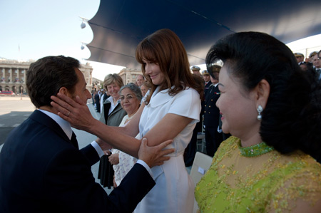 France's President Nicolas Sarkozy (L) speaks to his wife Carla Bruni-Sarkozy as he arrives at the Place de la Concorde in Paris to attend the Bastille day parade, July 14, 2009. [Xinhua/Reuters]