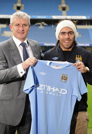 Manchester City's new signing Carlos Tevez (R) and coach Mark Hughes pose at a news conference at the City of Manchester stadium, northern England July 14, 2009. Tevez, who spent the last two seasons at United under a lease agreement after a spell with West Ham United, was Abu Dhabi-owned City's third major signing since the end of last season. (Xinhua/Reuters Photo) 