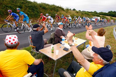 Spectators cheer the pack of riders during the tenth stage of the 96th Tour de France cycling race between Limoges and Issoudun, July 14, 2009.(Xinhua/Reuters) 