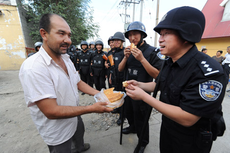 Mohammad presents his home-made food to members of the special police force on Pingding Hill in Urumqi, capital of northwest China's Xinjiang Uygur Autonomous Region, July 14, 2009. 