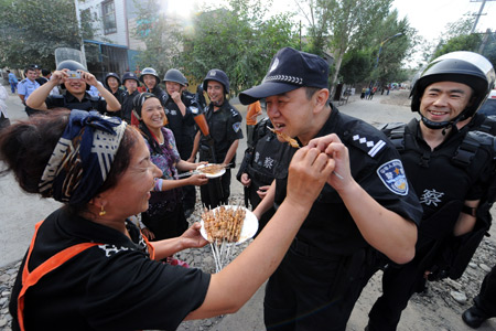Amyna presents her home-made kabob to members of the special police force on Pingding Hill in Urumqi, capital of northwest China's Xinjiang Uygur Autonomous Region, July 14, 2009.