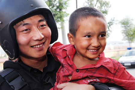 He Wei (L), a member of the special police force, poses with Uygur boy Enwa on Pingding Hill in Urumqi, capital of northwest China's Xinjiang Uygur Autonomous Region, July 14, 2009. 